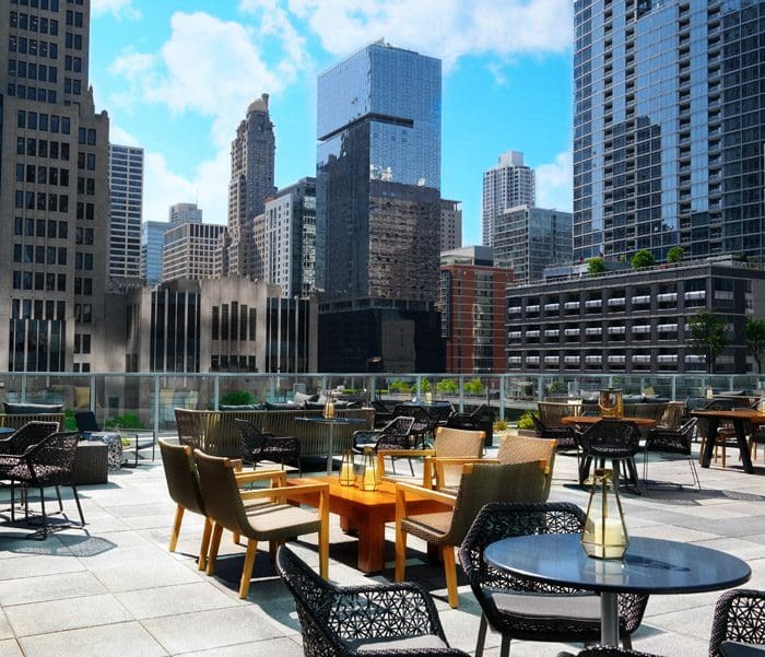 A rooftop view and terrace at the Loews Chicago Hotel, featuring a variety of seating and a view of the surrounding Chicago skyline.