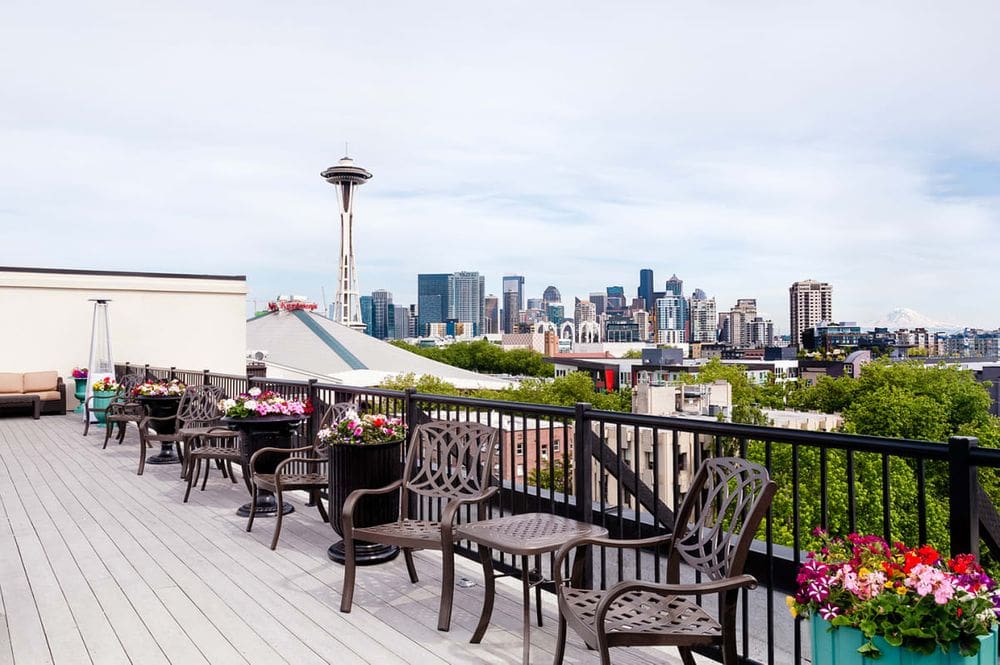 The roof-top terrace of the Mediterranean Inn, featuring a variety of seating and a view of the Space Needle, as well as the Seattle skyline.