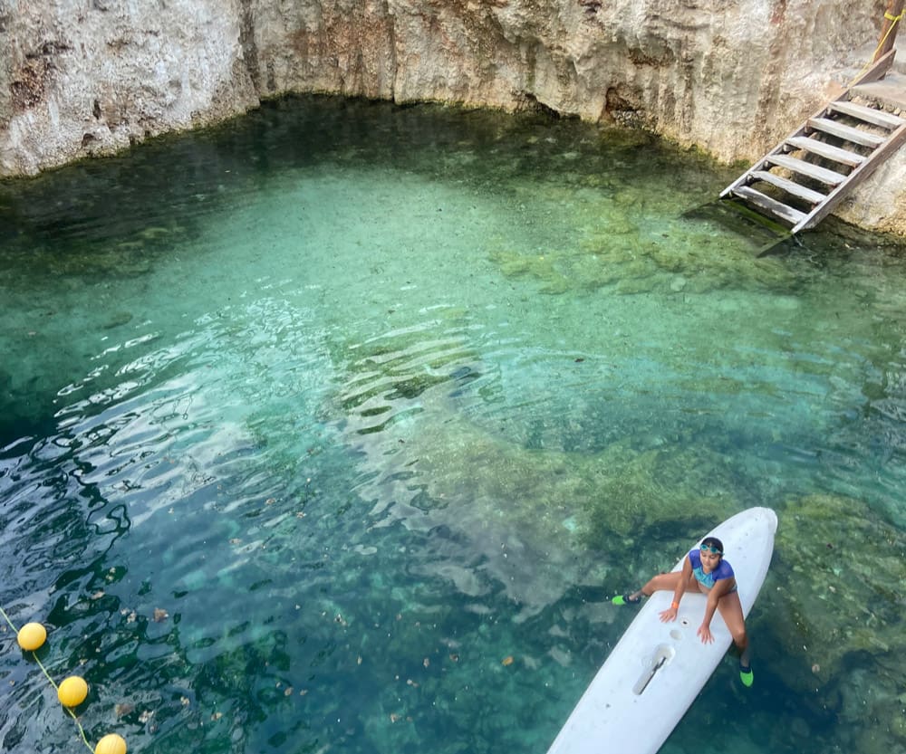 A young girl sits on a paddleboard while enjoying a cenote near Playa del Carmen.