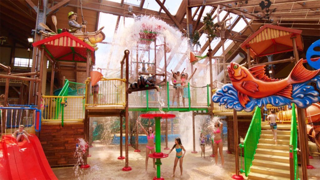 Several kids play together inside the Six Flags Great Escape Lodge & Indoor Water Park, featuring colorful splash areas.