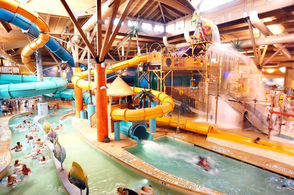Inside the Splash Lagoon Indoor Water Park, featuring huge slides, a lazy river, and several laughing families.