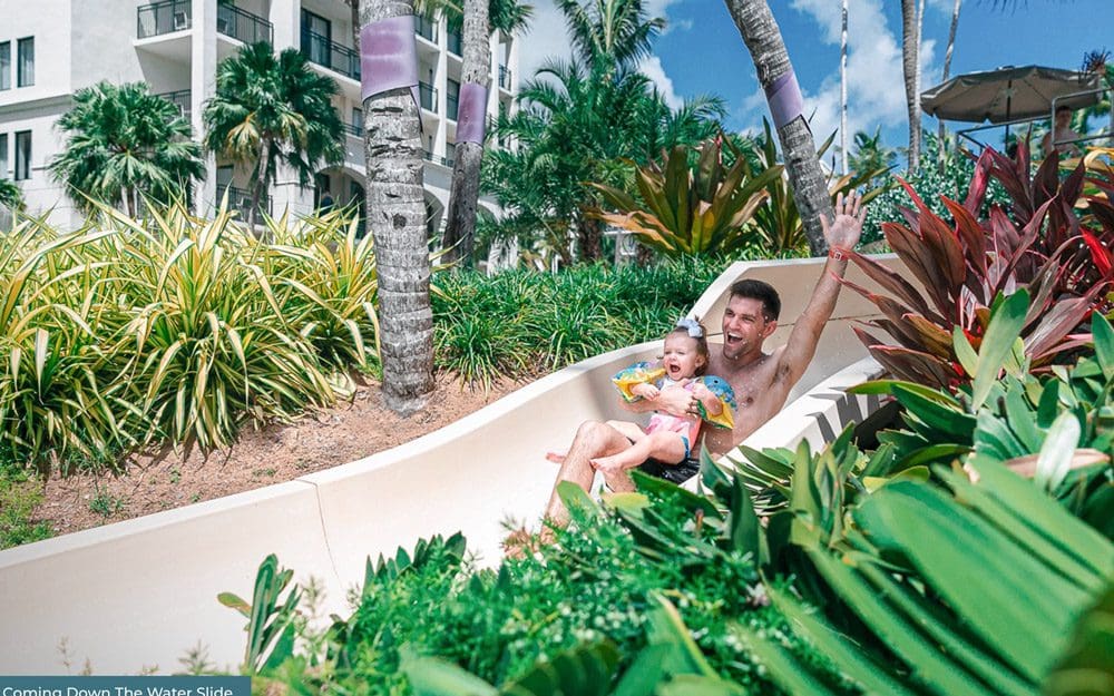 Picture of a father going down a waterslide with his daughter at the Wyndham Grand Rio Mar Puerto Rico Golf & Beach Resort.