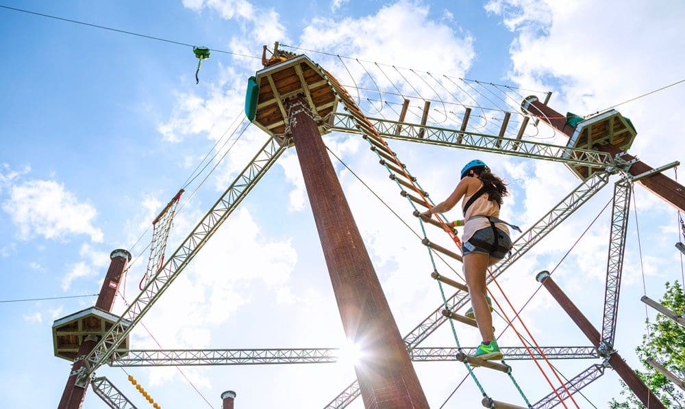 A woman climbs up a ropes course ladder at WildPlay Niagara Falls.