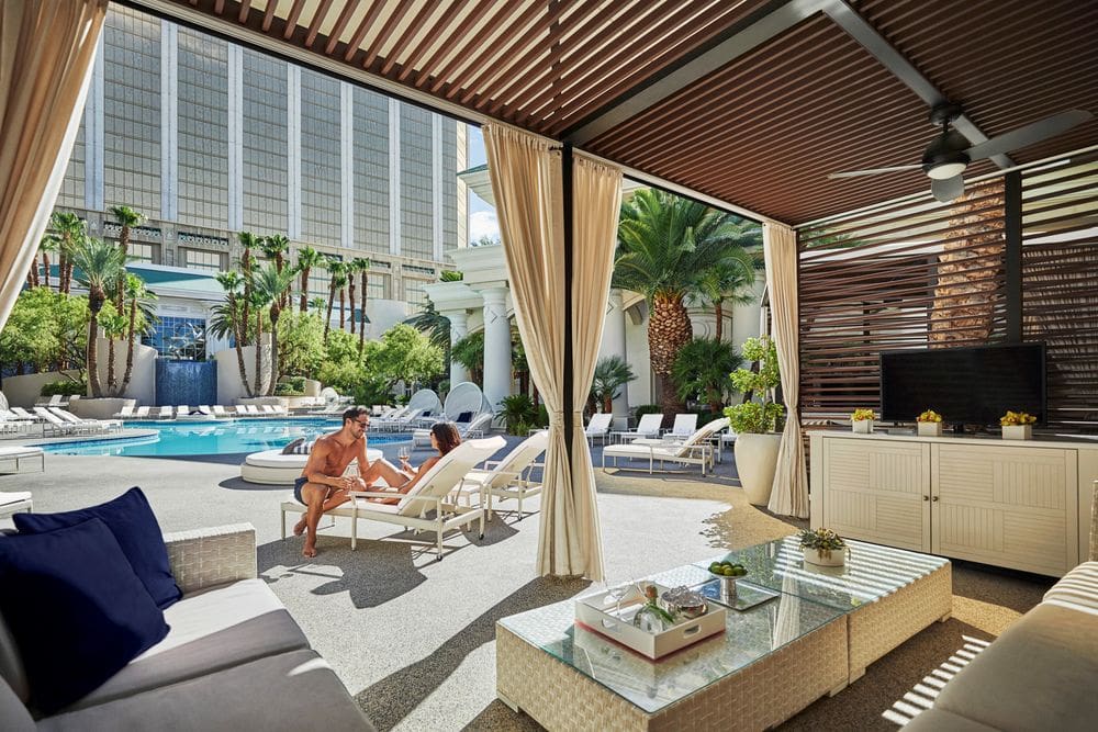A couple sit on a pool lounger together while enjoying a gorgeous day near the pool at Photo Courtesy: Four Seasons Las Vegas.