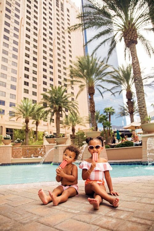 Two young children of color munch on popsicles near the pool at Hilton Grand Vacations on the Boulevard.