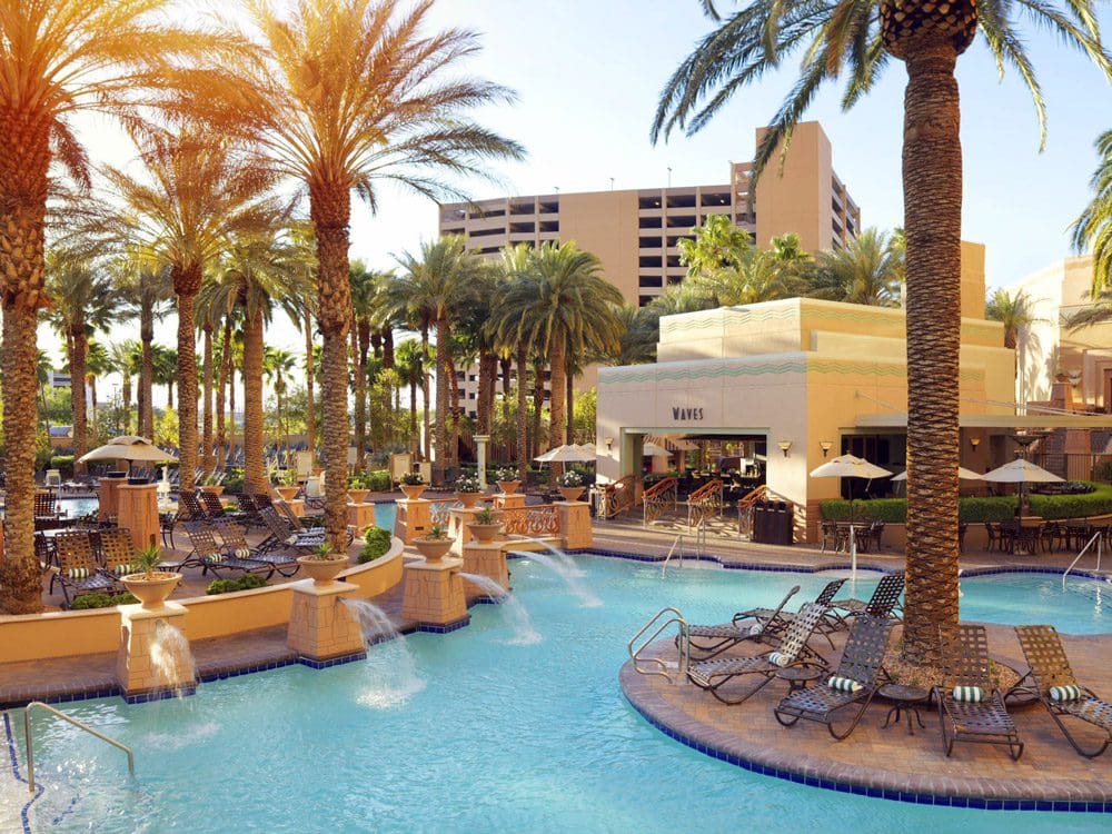 The outdoor pool, featuring palm trees and waterfalls, at Hilton Grand Vacations on the Boulevard, one of the best hotels in Las Vegas for families.