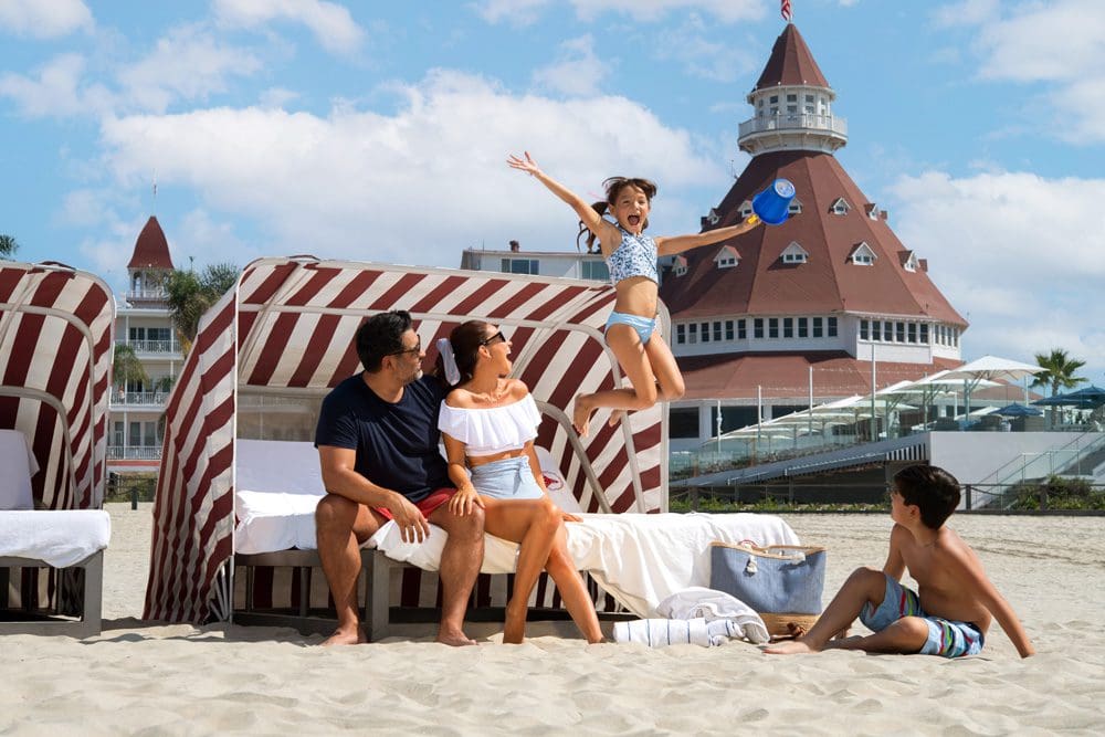 A family plays together on the beach at the Hotel Del Coronado, Curio Collection By Hilton.