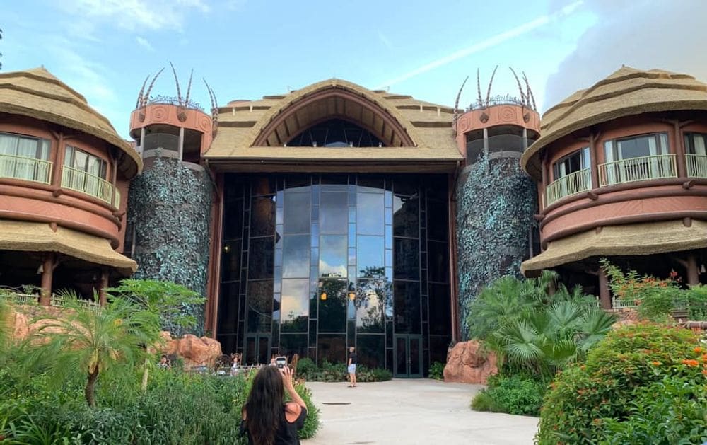 The exterior of the Animal Kingdom Lodge, featuring its iconic feathered towers and glass entrance, a great Disney Deluxe Resort for families.