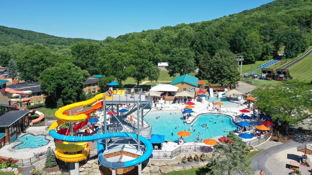 An aerial view of the outdoor pool and waterpark at the Rocking Horse Ranch, including several pool deck loungers and more.