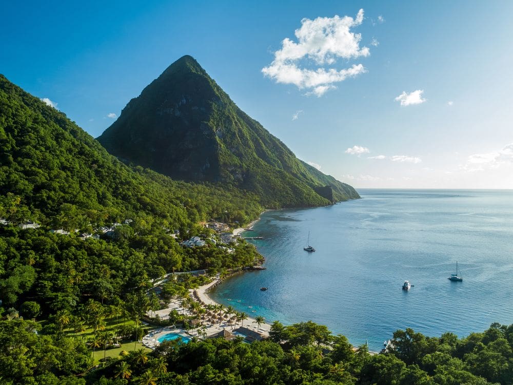 An aerial view of Sugar Beach, A Viceroy Resort, with a sprawling beach and view of the pitons in St. Lucia, one of the best all-inclusive resorts in the Caribbean for families.
