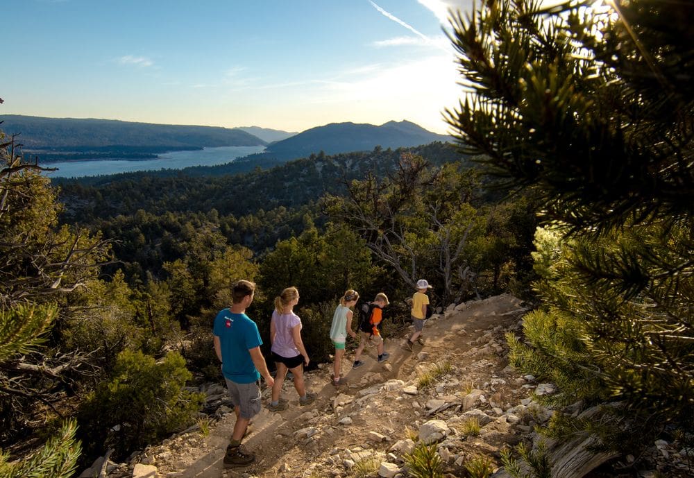 A family of five walks along a trail near Big Bear, California on a crisp autumn day, one of the best places for fall in California with kids.