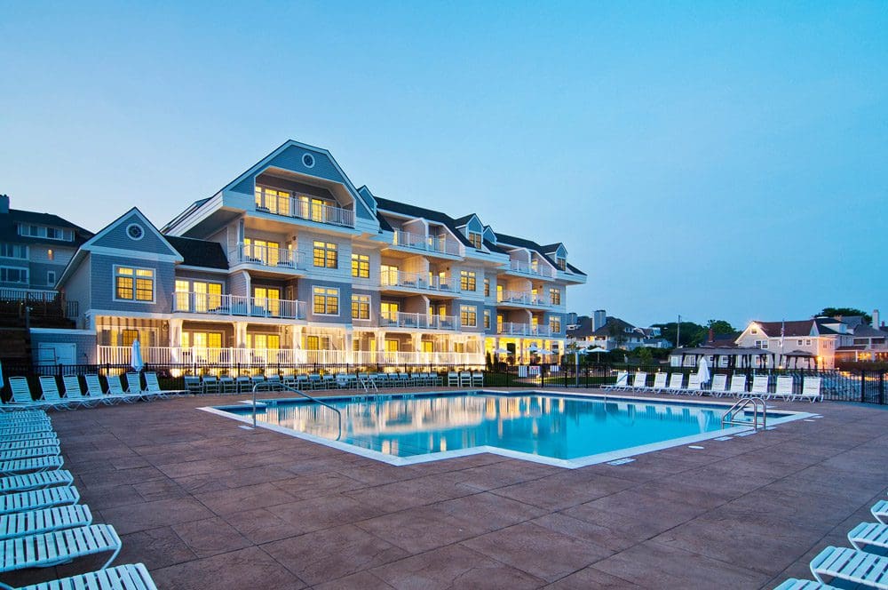 The back of the Water’s Edge Resort and Spa lit up at night, overlooking the pool and pool deck.