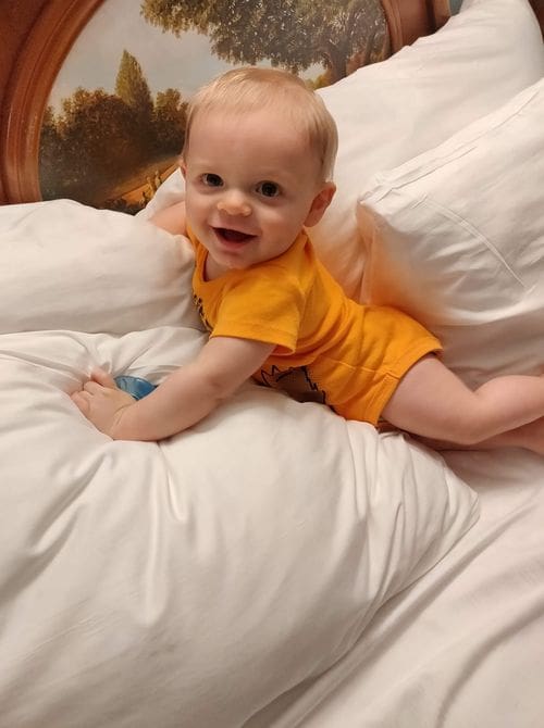 A baby sits on a comfy bed at Disney's Port Orleans - Riverside Resort, one of the best Disney moderate resorts for families.
