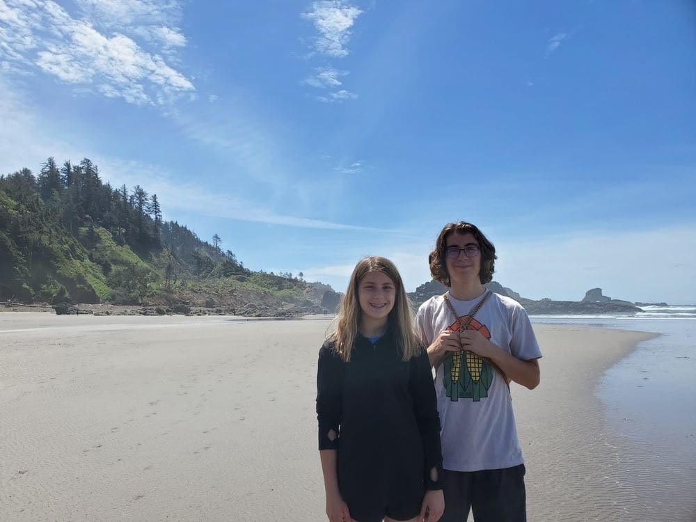 Two teenagers stand together on Indian Beach in Ecola State Park.