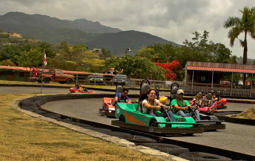Several people in small cars race around a track at the Carabalí Rainforest Park.