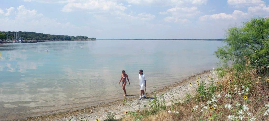 Two people walk along a beach at Cedar Hills State Park in Arlington.