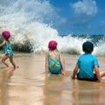 Children on the beach, a big wave, the child runs away in fright. Playa Los Tubos (Manati, Puerto Rico).