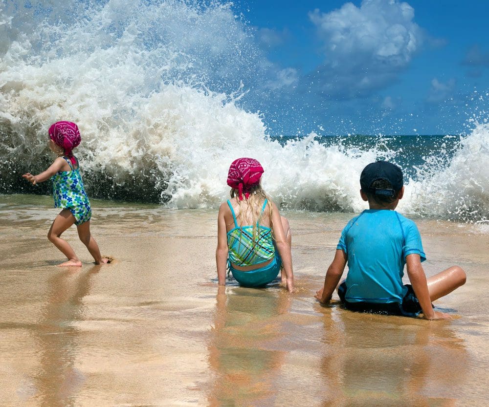 Children on the beach, a big wave, the child runs away in fright. Playa Los Tubos (Manati, Puerto Rico).