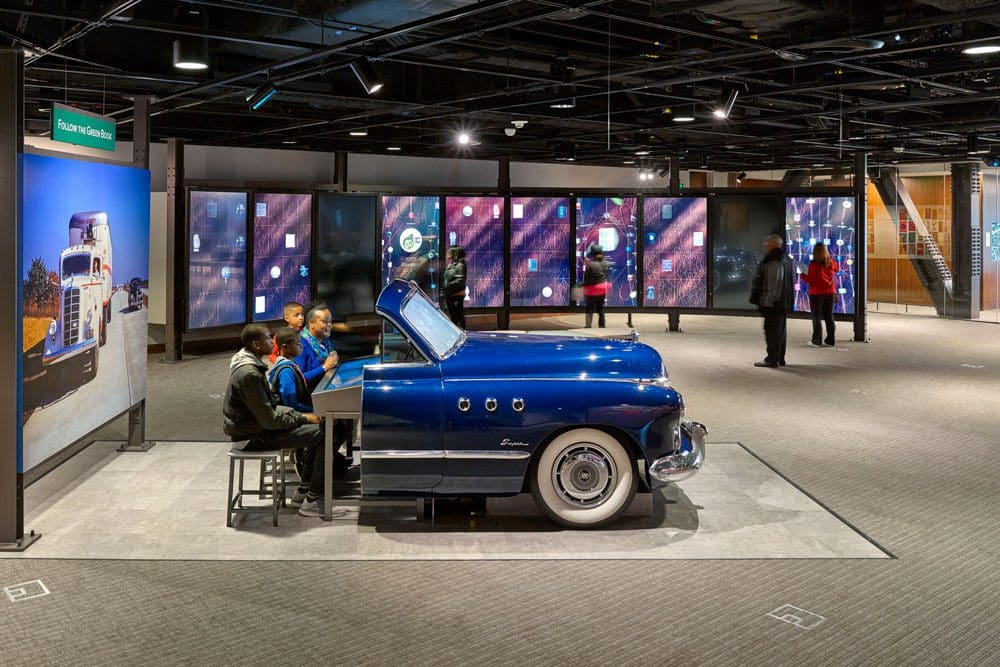 A blue exhibit car holds several people at the National Museum of African American History and Culture.