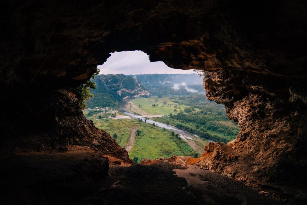 Looking through a hole in a cave wall onto a Puerto Rican country-scape.