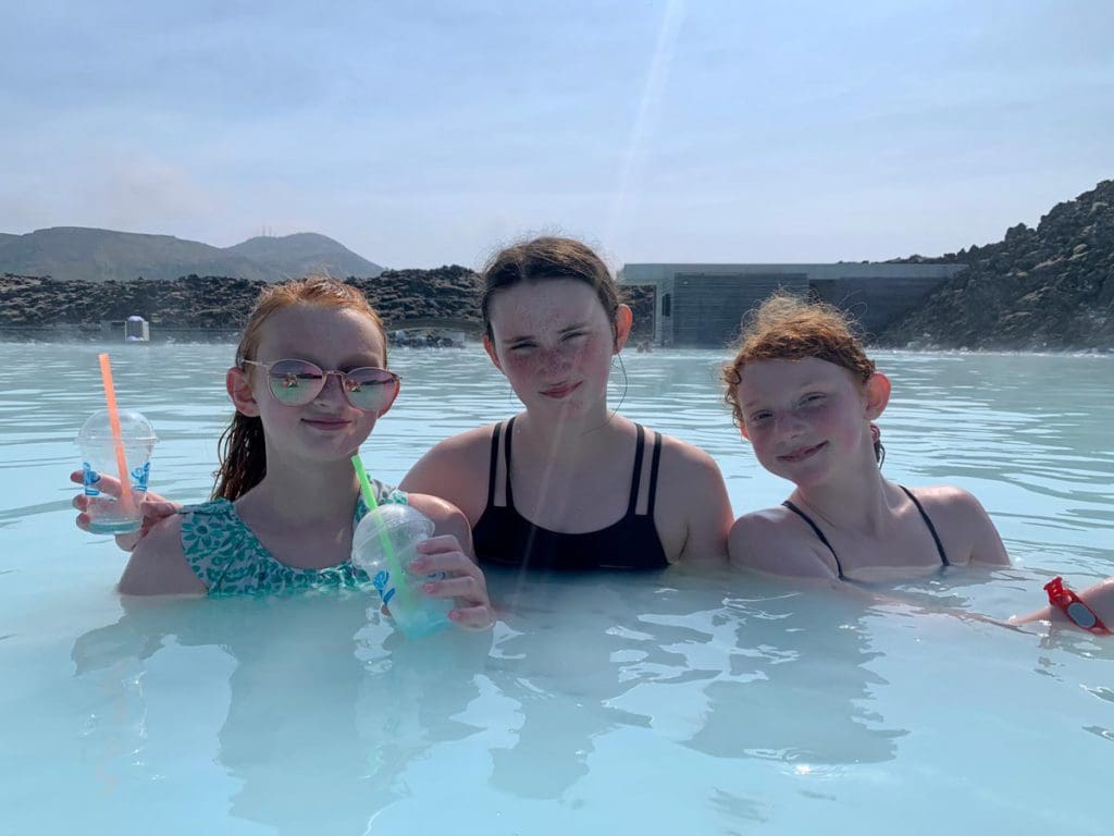 Three pre-teen girls enjoy a hot spring in Iceland, one of the top places in travel in 2023 with kids.