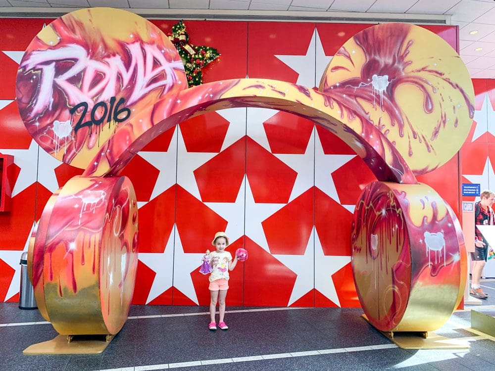 A young girl stands under a huge pair of headphones at Disney's All-Star Music Resort.