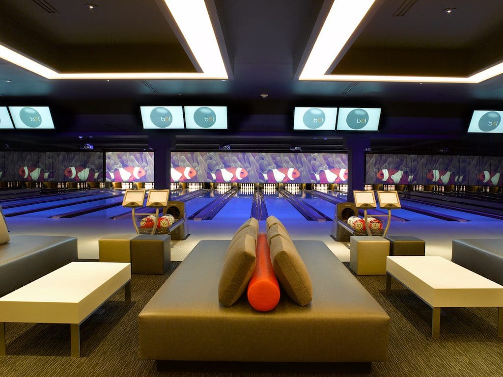 Inside the bowling alley at Deca+Bol, featuring blue and orange hued lights and furnishings, a must do when visiting Vail in the winter with kids.