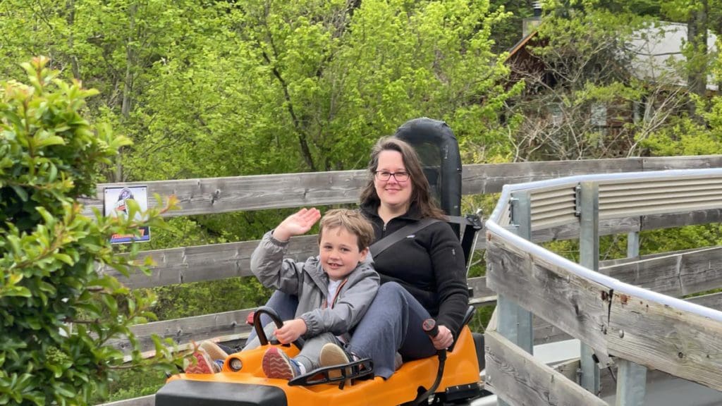 A mom and her young son wave from an alpine coaster.