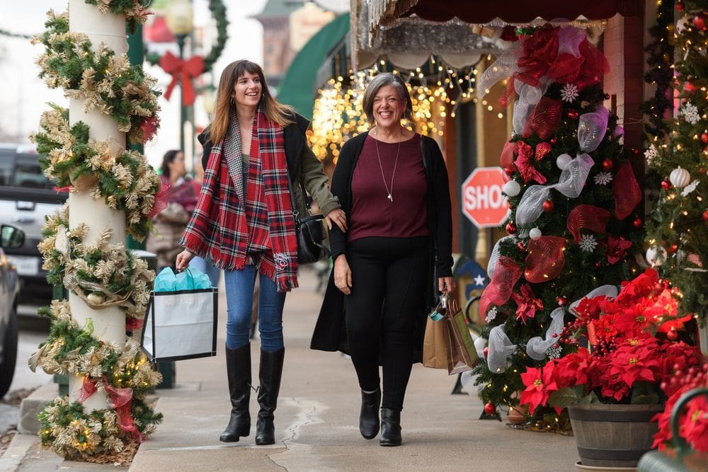A mother and daughter do some shopping in Grapevine, Texas, on a holiday-decor lined street.