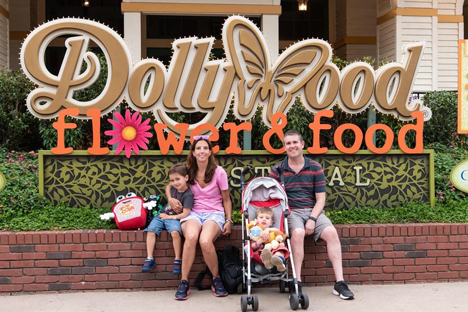 A family of four sits outside, in front of the sign for Dollywood Flower & Food.
