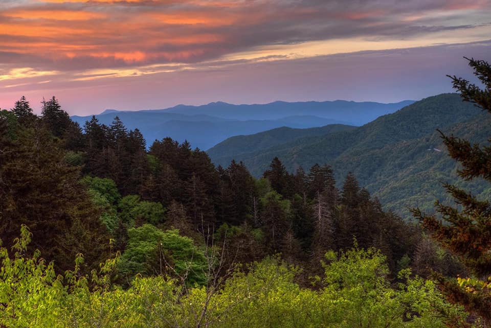 A stunning sunrise over the Smoky Mountains at Clingman's Dome, featuring hues of orange, pink, and blue, one of the best things in a family itinerary for Gatlinburg Pigeon-Forge.