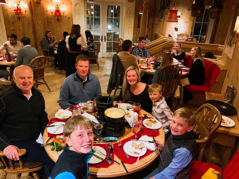 A multi-generational family eats around a round table at the Swiss Chalet Restaurant, one of the best places to eat in Vail in the winter with kids.