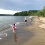Three kids in bathing suits walk down Playa Panama in Costa Rica.