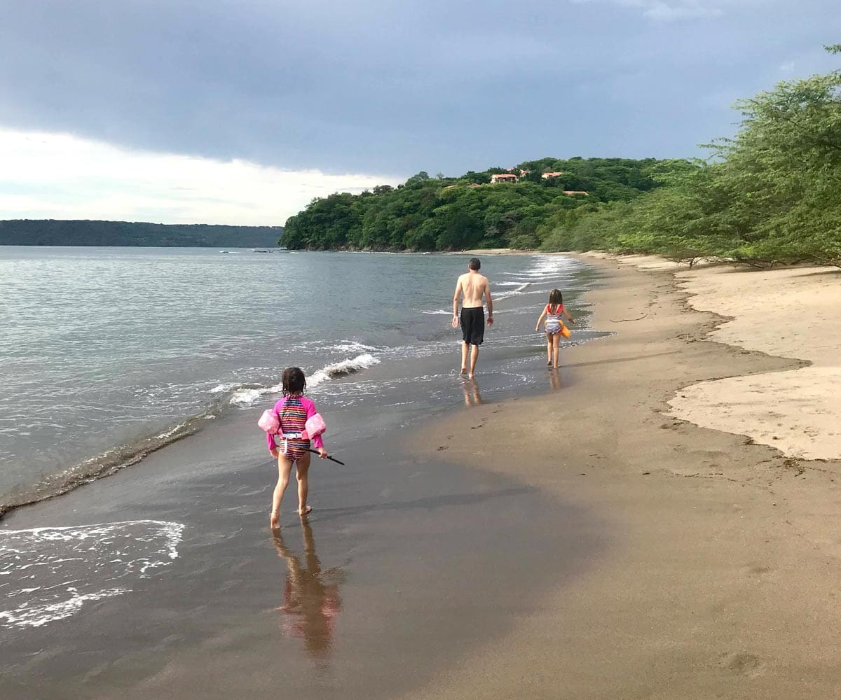 Three kids in bathing suits walk down Playa Panama in Costa Rica.