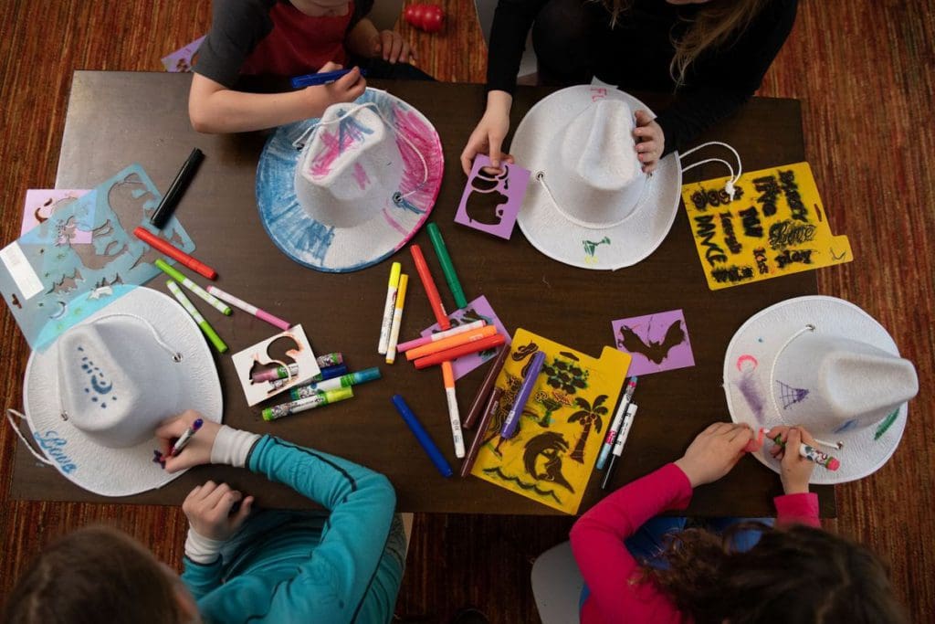 An aerial view of four kids decorating cowboy hats while spending time at the The Ritz-Carlton, Bachelor Gulch kids' club.