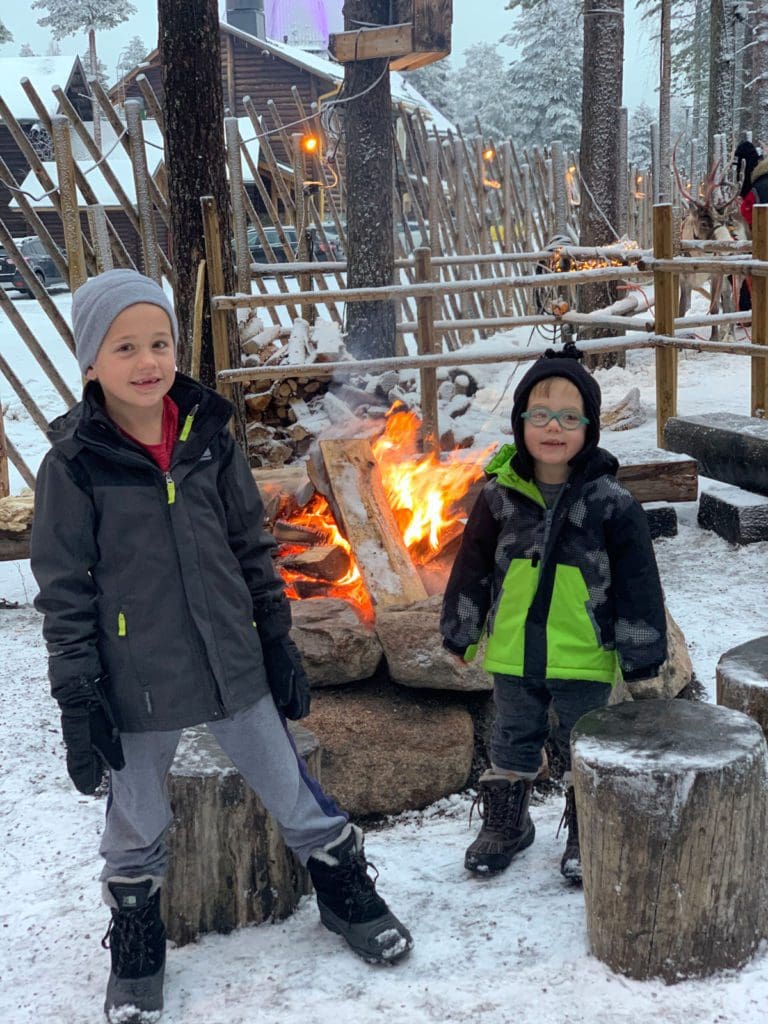 Two young boys stand near a bon fire while at Santa's Village in Lapland.