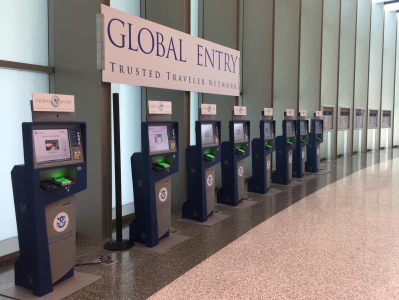 The global entry station at an airport, featuring eight empty kiosks. Use the Capital One Venture X Card for family reimbursement up to $100.
