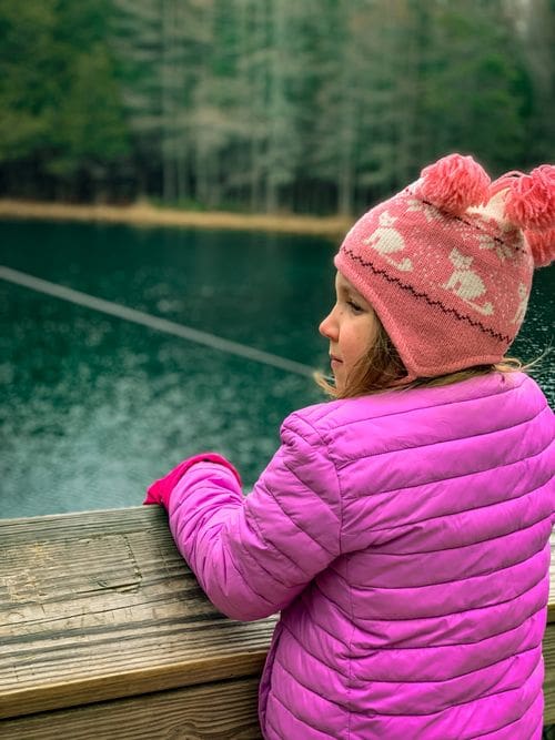 A girl looks over the raft ledge at the turquoise waters of Kitch-iti-kipi, one of the best places to visit in Michigan’s Upper Peninsula with kids.