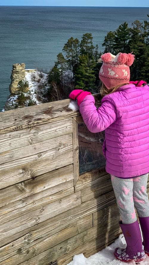 A young girl looks over a ledge at Miners Castle.