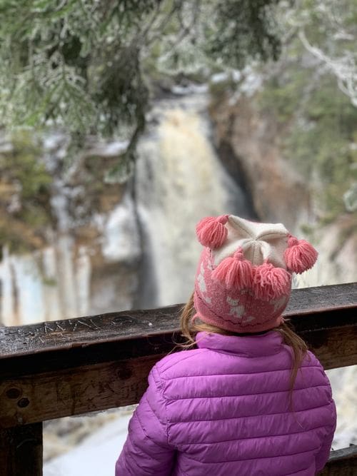 A young girl looks over the balcony of a viewing platform at Miners Falls, one of the best Upper Peninsula Michigan hikes for families.