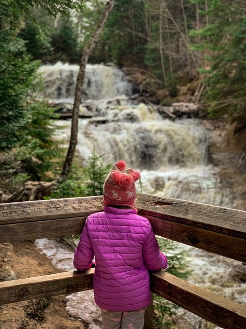 A young girl looks at Sable Falls from a viewing platform.