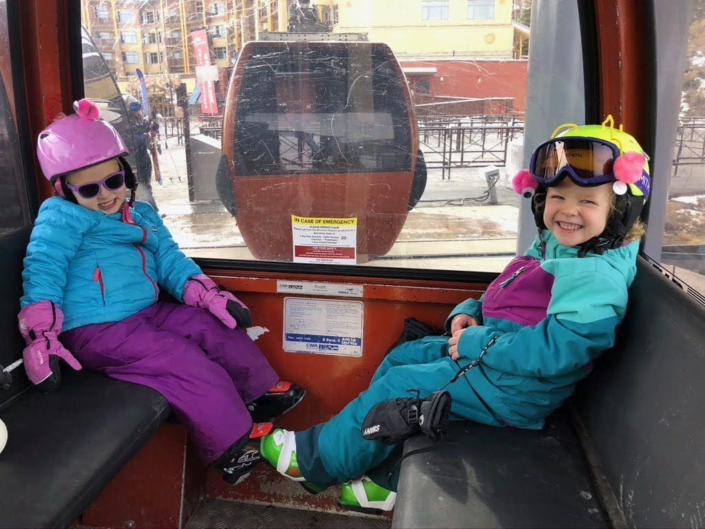 Two kids ride the gondola in full ski gear, while visiting Deer Valley.