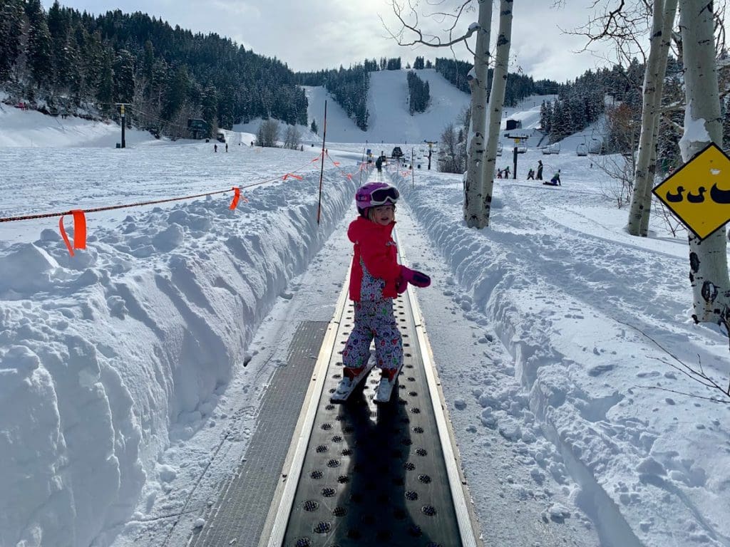 A young girl rides the magic carpet up the ski run in Park City.