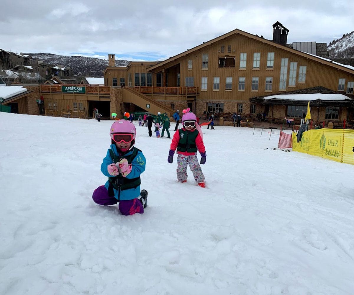 Two kids play in the snow outside of a resort in Park City.