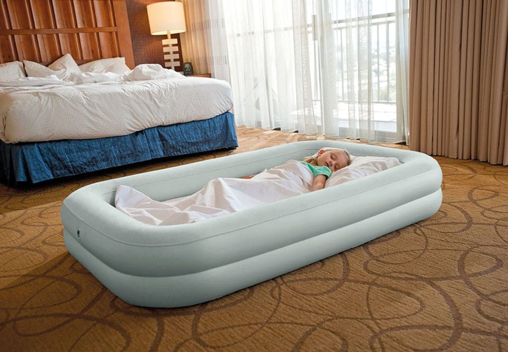 A young girl sleeps in a Intex Kids Travel Bed Set in a hotel room while traveling with her family.