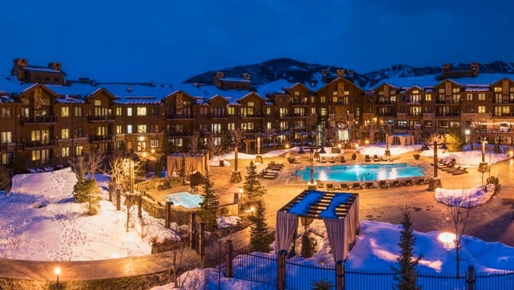 The exterior of the Waldorf Astoria Park City at night, featuring the building, pool, and grounds.