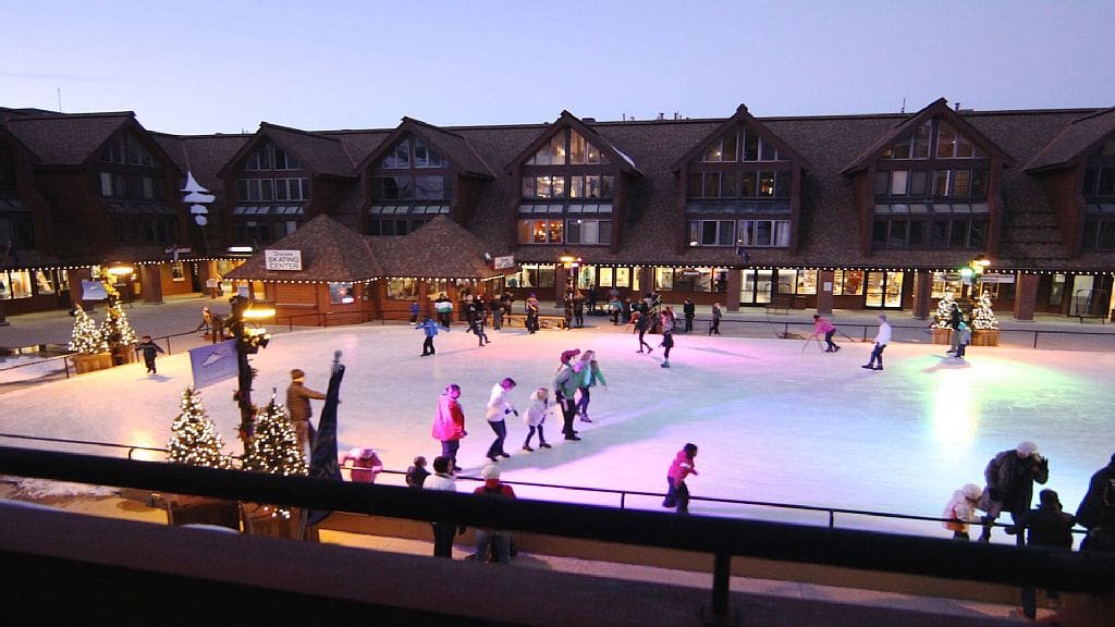 Several people skate around the ice at the Resort Center Ice Skating Rink, one of the best things to do when visiting Deer Valley with kids.