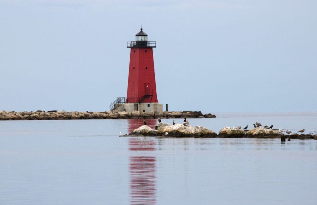 A red lighthouse with a rocky walk at Manistique Boardwalk, one of the best Upper Peninsula Michigan hikes for families.