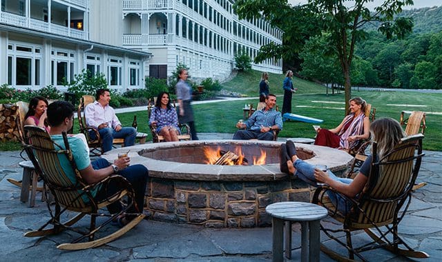 Several people sit around a fire pit on a beautiful night at the Omni Bedford Springs Resort.