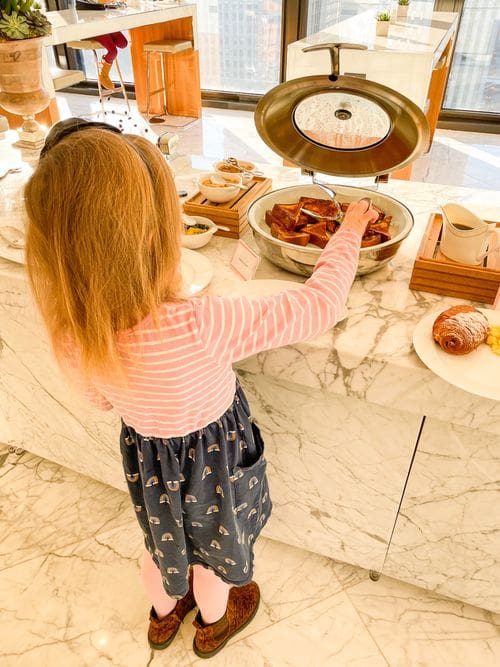 A young girl takes french toast from a breakfast display at The Langham, Chicago.